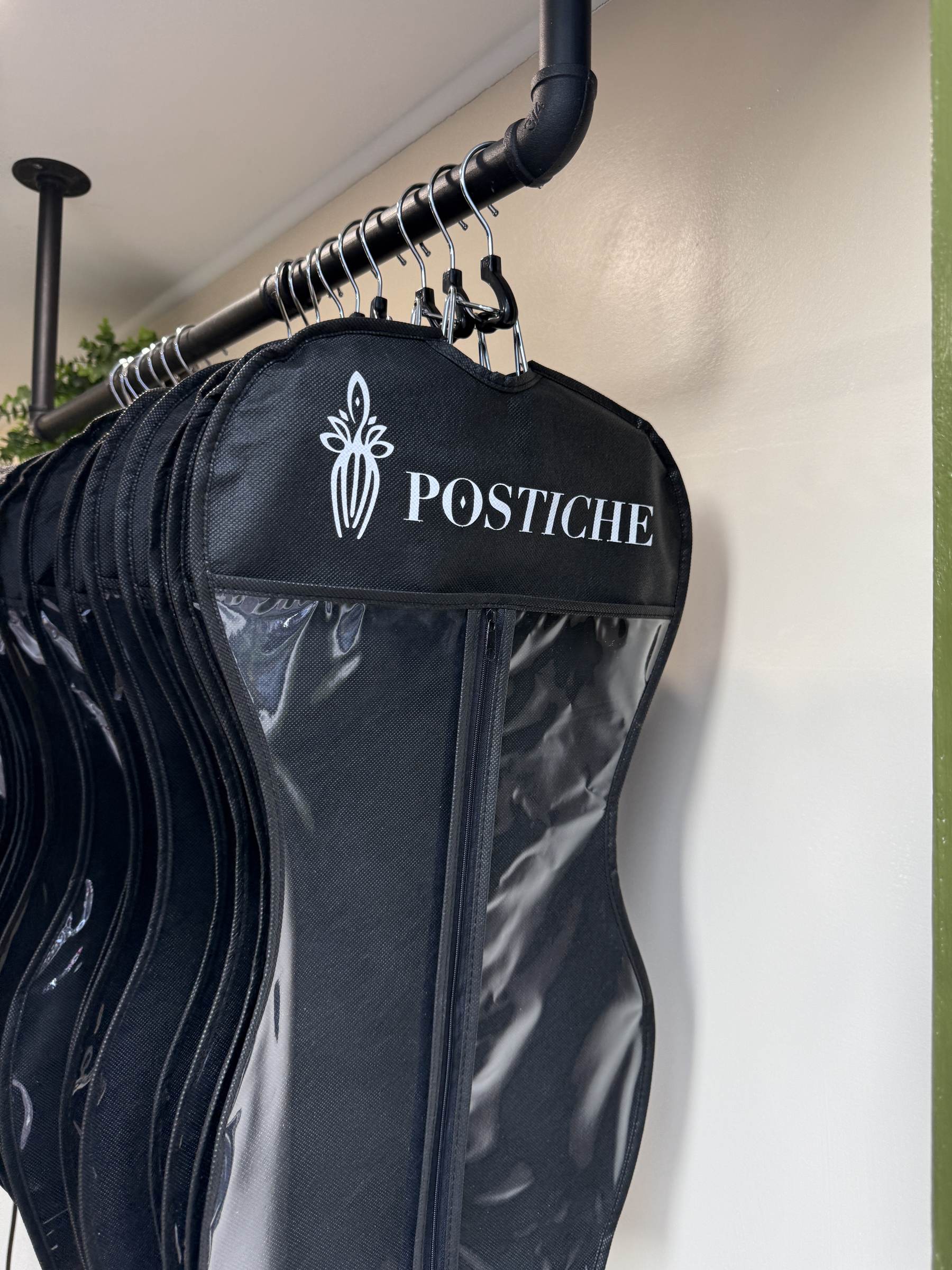 Postiche-branded wig garment bags hanging inside the Traveling Studio