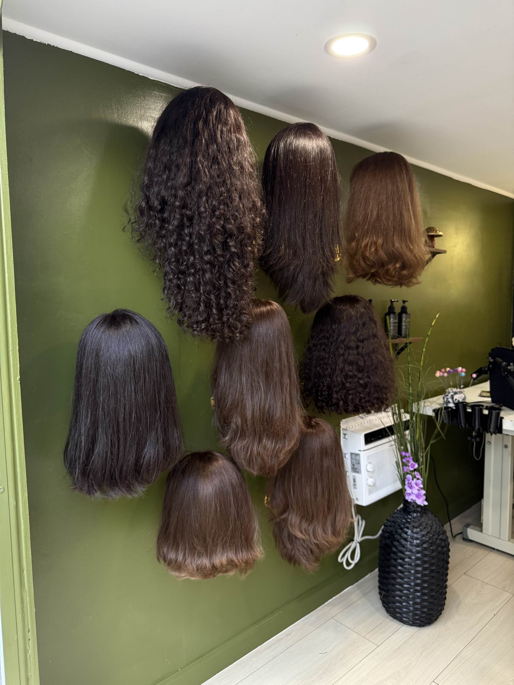 A wall display of wig styles and textures inside the Traveling Studio